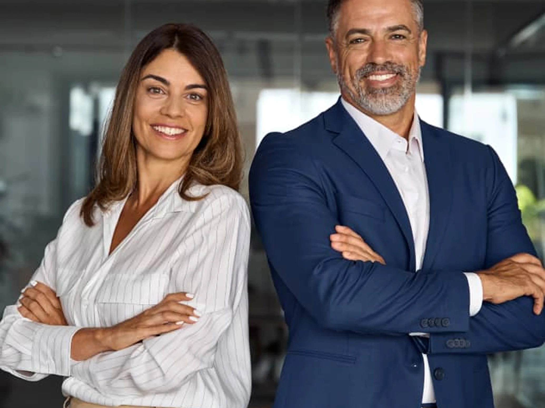 A woman and a man in business attire standing with arms crossed